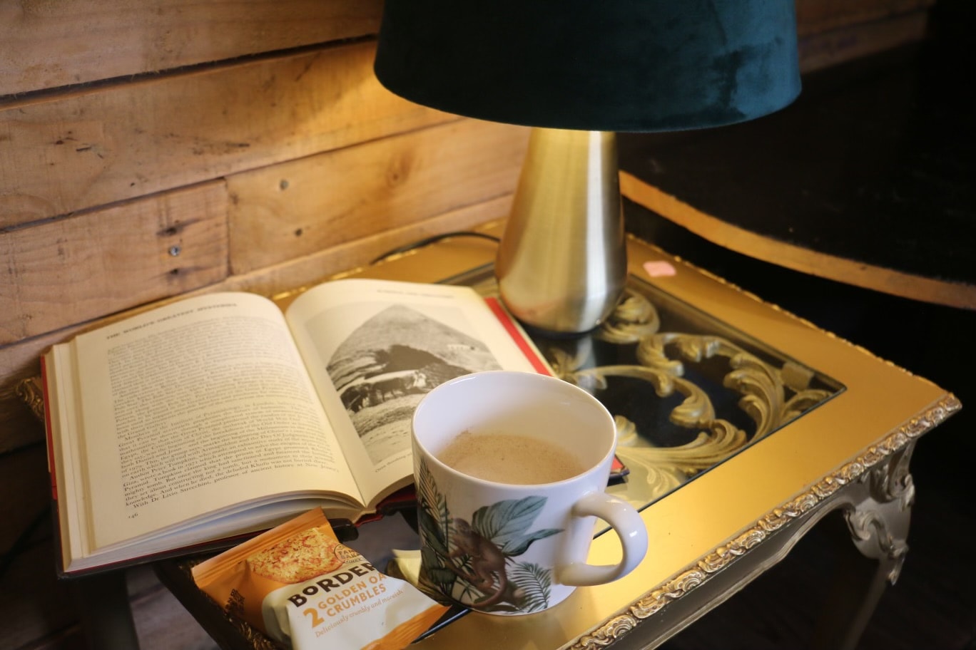 Cosy reading nook with book, coffee and lamp on gold side table