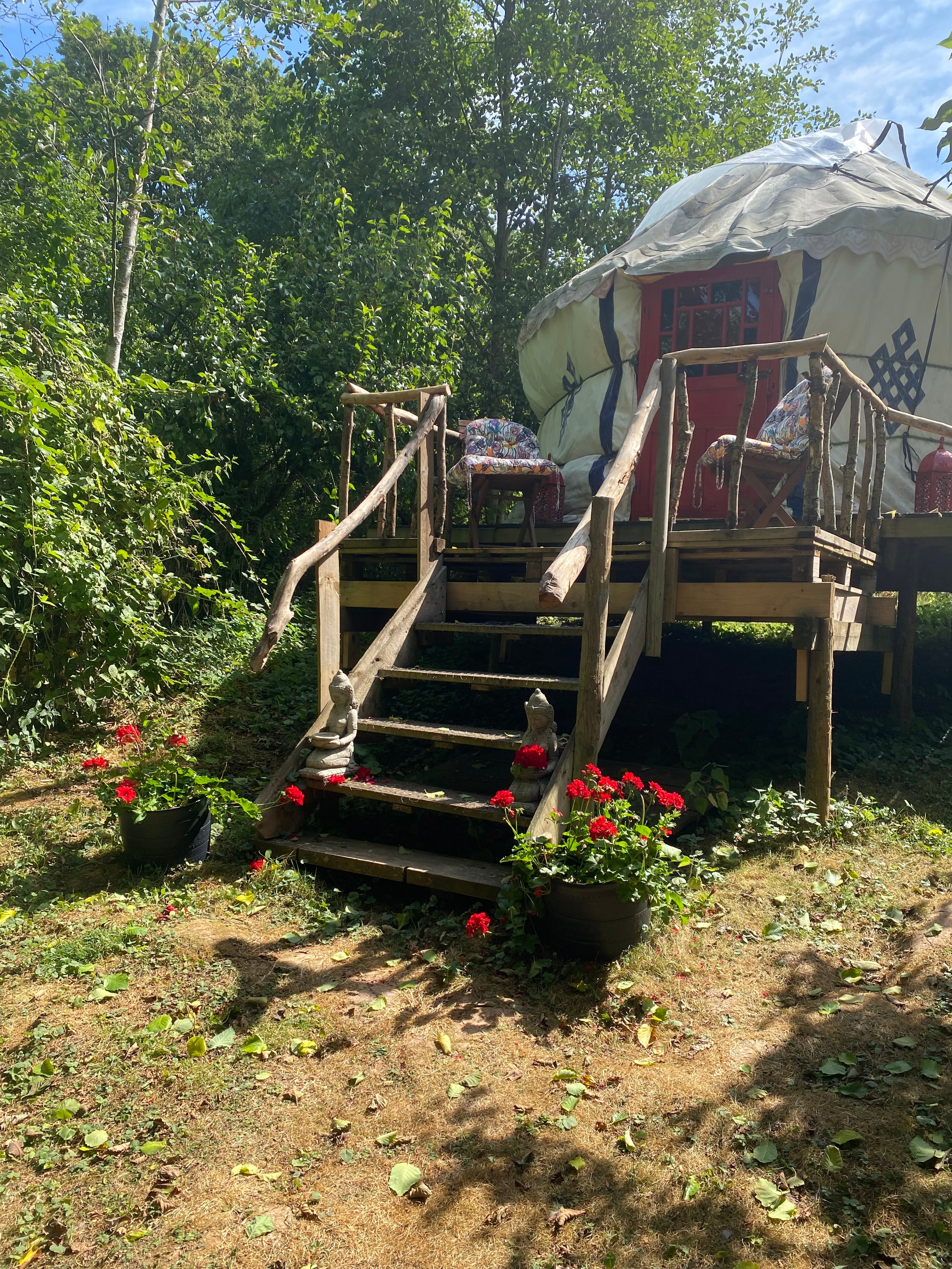Yurt exterior with rustic wooden steps and red flowers